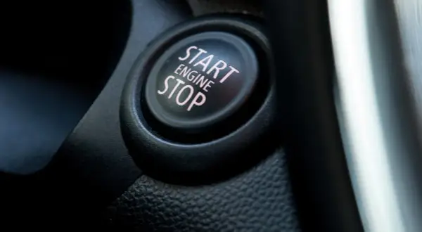Nahaufnahme eines Start/Stop-Knopfes im Auto. Der Knopf ist schwarz mit rosa Schrift.