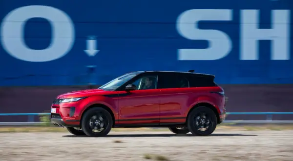 Roter Range Rover Evoque 2022 fährt an blauer Wand mit weißen Buchstaben vorbei.