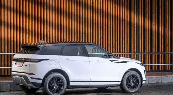 Weißer Range Rover Evoque 2.0 Diesel, moderne Optik vor Holzfassade. Gute Range Rover Evoque 2.0 Diesel Erfahrungen gesucht?