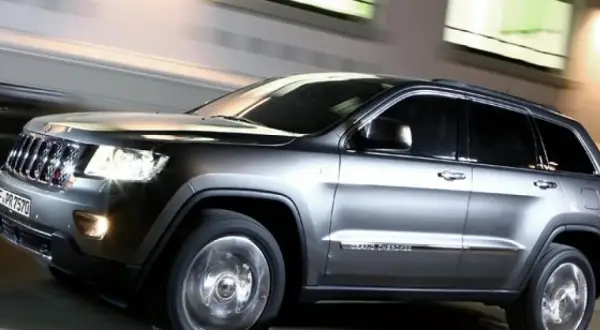Grauer Jeep Grand Cherokee 3.0 CRD 250 PS in Bewegung, der auf der Straße fährt. Mögliche Probleme mit dem Motor sind hier nicht sichtbar.