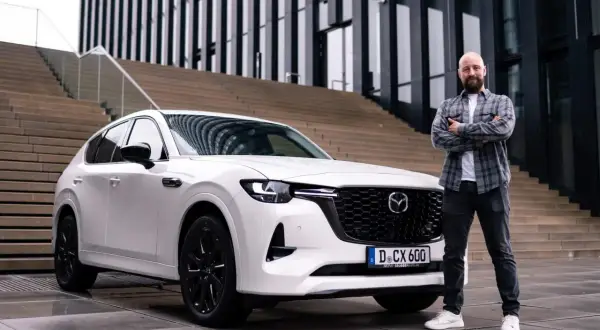 Mann steht neben weißem Mazda CX-60. Der Wagen ist bereit für den Mazda CX-60 Test.