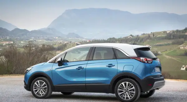 Blauer Opel Crossland parkt in malerischer Berglandschaft. Keine Probleme mit diesem Auto, nur Fahrspaß!
