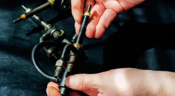 Hände halten Diesel-Einspritzdüsen. Ein Grund, warum der Motor ruckelt im Stand, könnte eine defekte Düse sein.