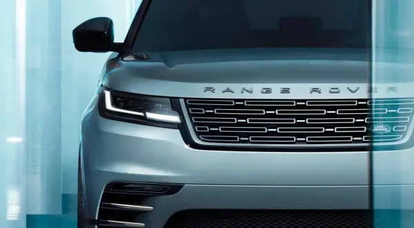 Der Kühlergrill eines silbernen Range Rover mit dem Schriftzug "RANGE ROVER" und dem Land Rover Logo. Ein Fahrzeug, das "land rover approved" ist.