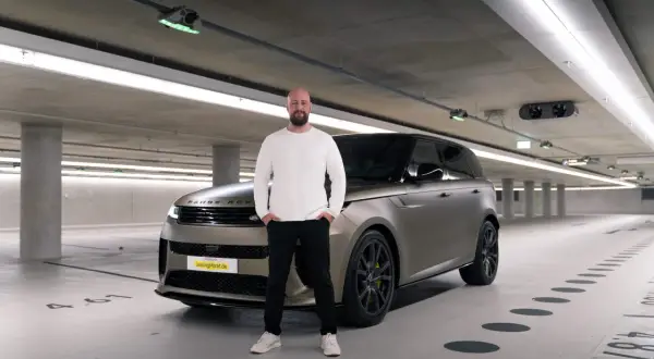 Mann steht neben einem Range Rover in einer Tiefgarage. Erste Range Rover Erfahrungen gesammelt.