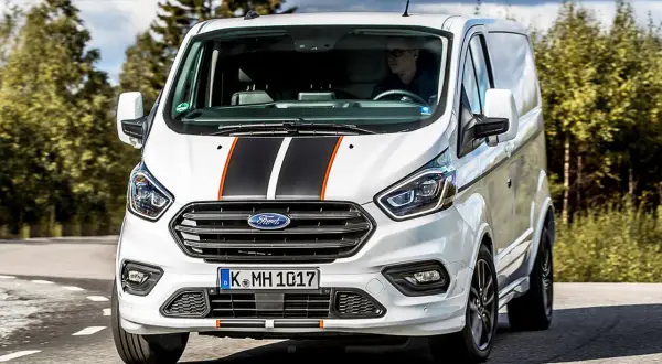 Weißer Ford Transit Custom mit Sportstreifen, Fahrer im Blick. Keine Probleme hier, nur ein stilvoller Transporter auf der Straße.