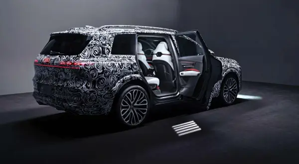 Der Audi SQ9, getarnt mit einem auffälligen Muster, zeigt seine luxuriösen weißen Ledersitze und die sportlichen Felgen.
