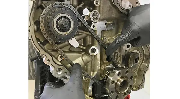 Hände prüfen die Steuerkette eines Motors. Die Frage, wie lange hält eine steuerkette, hängt von Wartung und Material ab.