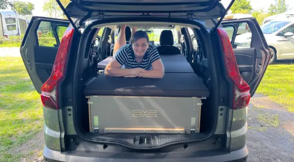 Frau liegt auf Bett im Dacia Jogger, bereit für den Camping-Test.