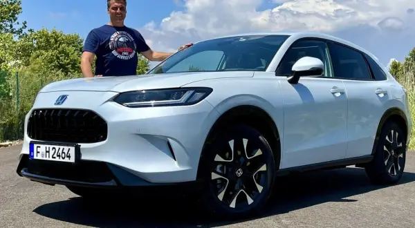 Mann steht neben einem weißen Honda ZR-V.