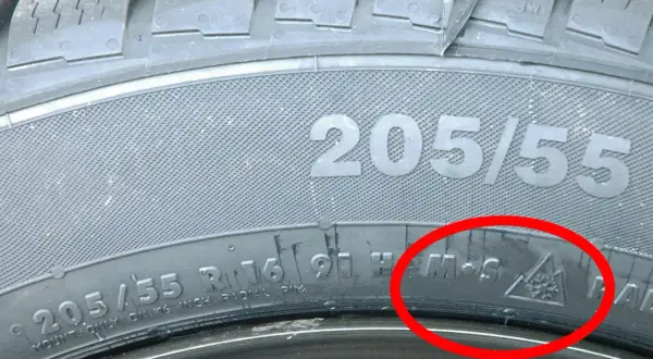 Detailaufnahme eines Reifens mit der Kennzeichnung 205/55 R16. Das alpine Zeichen (Schneeflocke im Berg) bestätigt, dass dies ein Winterreifen ist.