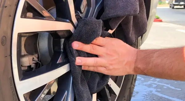Hand poliert Felge mit schwarzem Tuch. Ein einfacher felgenreiniger hausmittel-Trick für glänzende Räder.