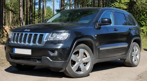 Schwarzer Jeep Grand Cherokee 3.6 V6 im Wald. Hoffentlich keine Probleme mit diesem Geländewagen.