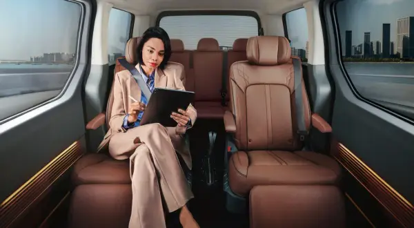 Frau arbeitet im luxuriösen Hyundai Staria Innenraum, während sie durch eine Stadt fährt.