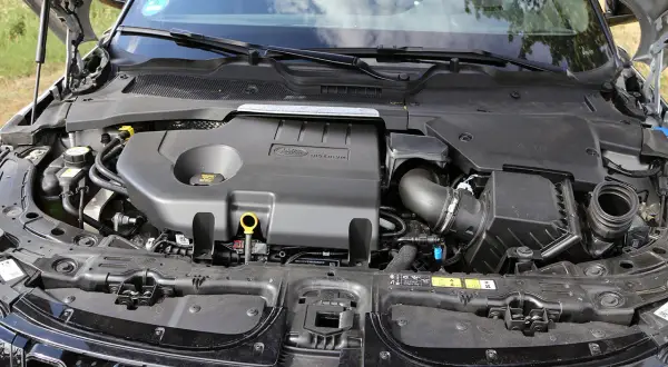 Motorraum eines Range Rover Evoque. Der Motor ist abgedeckt, aber die Leistung des Fahrzeugs, die durch die PS angegeben wird, ist spürbar.