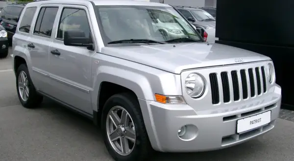 Silberner Jeep Patriot, der auf einem Parkplatz steht. Bekannt für seine Robustheit, aber auch für seine Jeep Patriot Schwachstellen, wie z.B. Rost an den Radläufen.