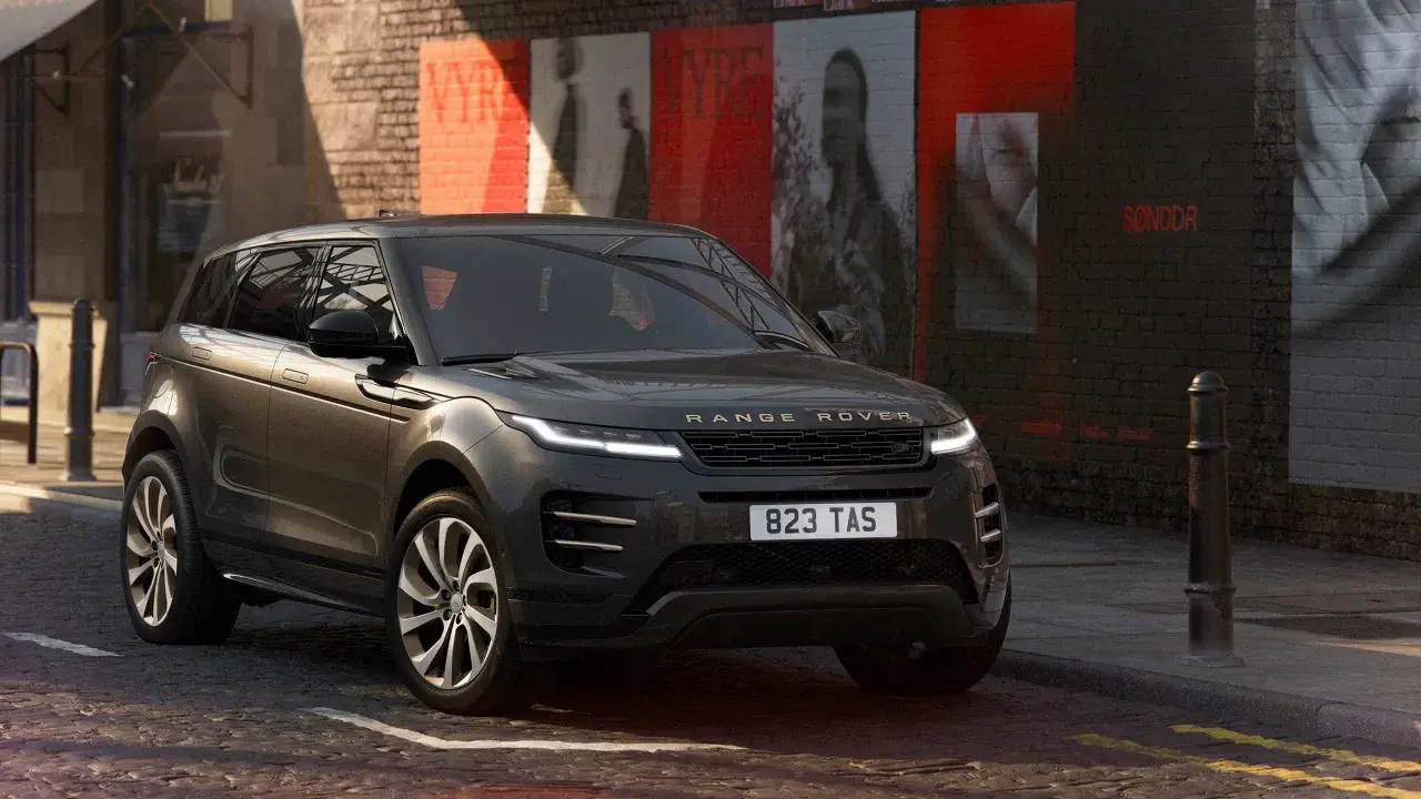 Dunkelgrauer Range Rover Evoque Black Edition parkt in einer Gasse mit Graffiti an der Wand.