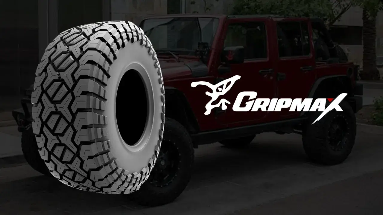 Ein grobstolliger Reifen von Gripmax neben einem roten Jeep. Perfekt für jedes Abenteuer.