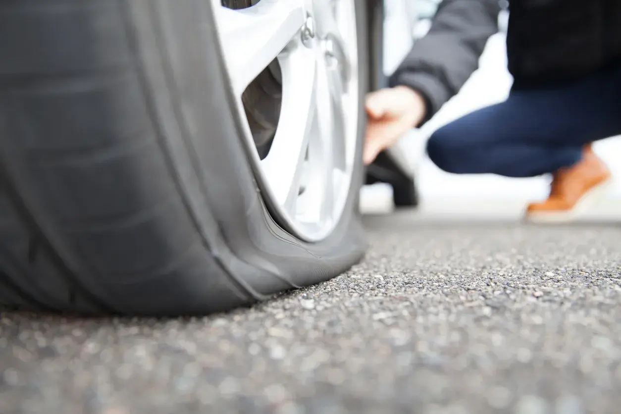 Ein Auto mit platten Reifen steht auf Asphalt. Die Frage ist, wie lange kann ein Auto auf einem platten Reifen stehen, bevor es beschädigt wird?
