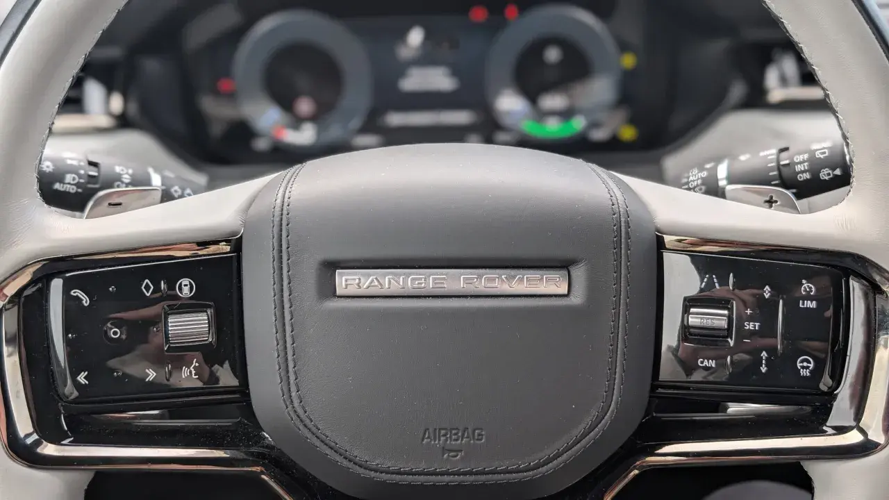 Nahaufnahme des **Range Rover Lenkrads** mit Bedienelementen für Tempomat und Infotainment.