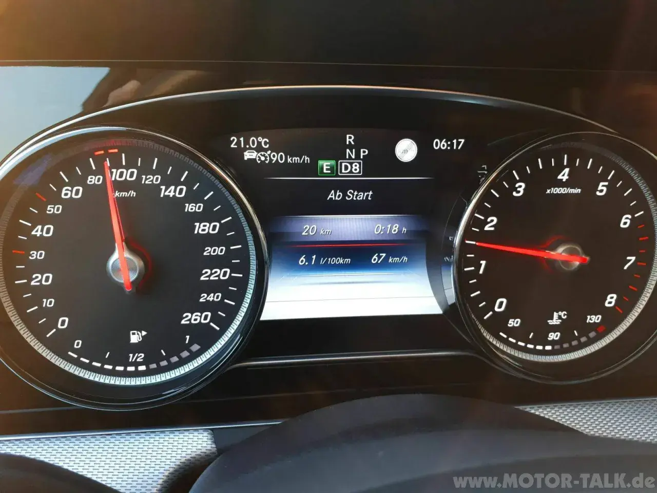 Fahrzeug-Display eines Mercedes mit Tacho bei 90 km/h, Verbrauchsanzeige und aktiver Tempomat-Funktion.