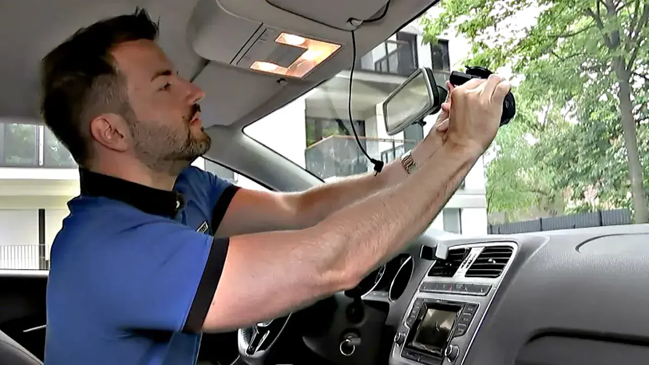 Mann montiert eine Dashcam im Auto. So kann er seine Fahrten aufzeichnen und sein Fahrzeug nachrüsten.