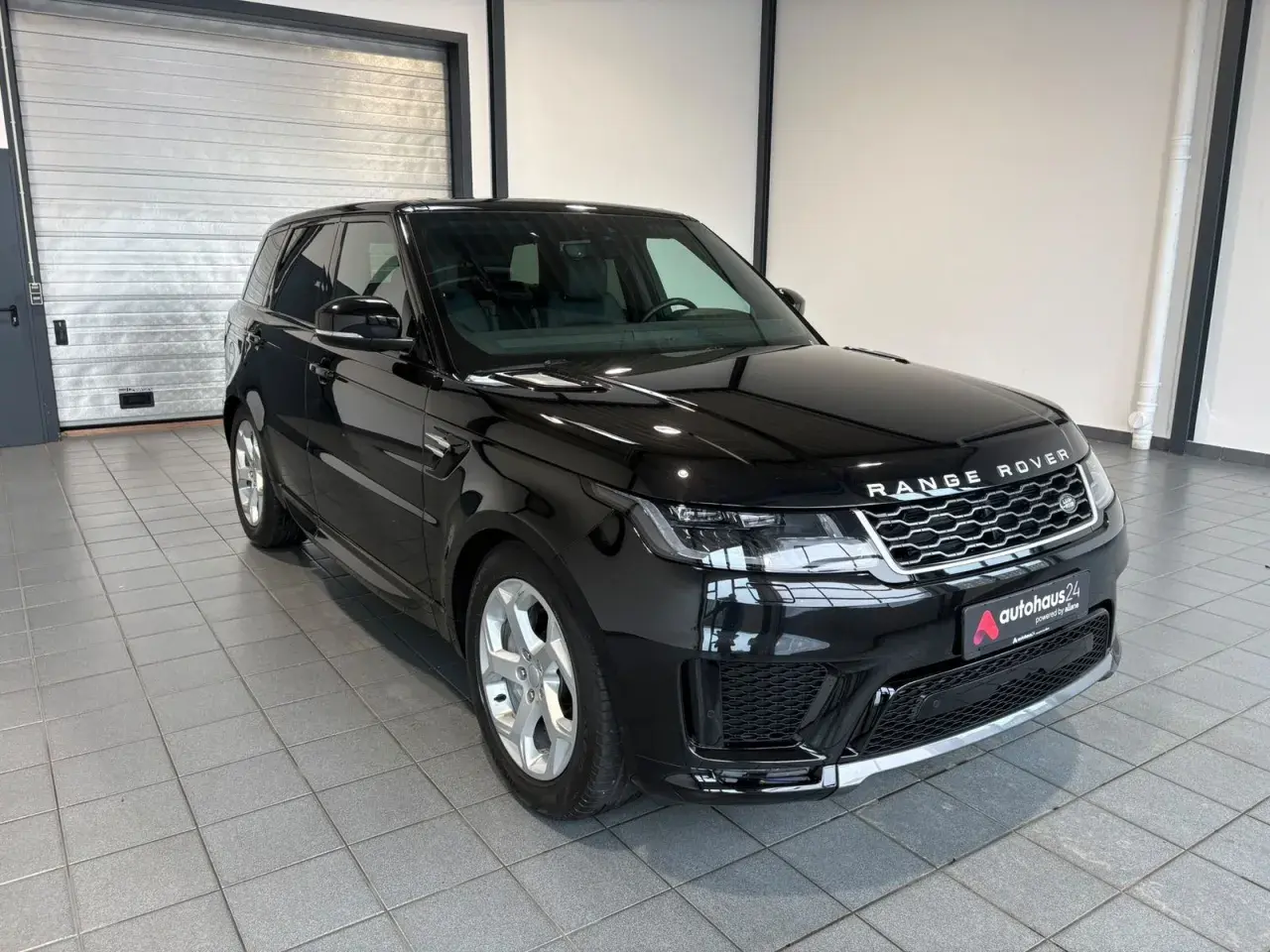 Schwarzer Range Rover Sport gebraucht Automatik mit silbernen Felgen steht in einer Garage.