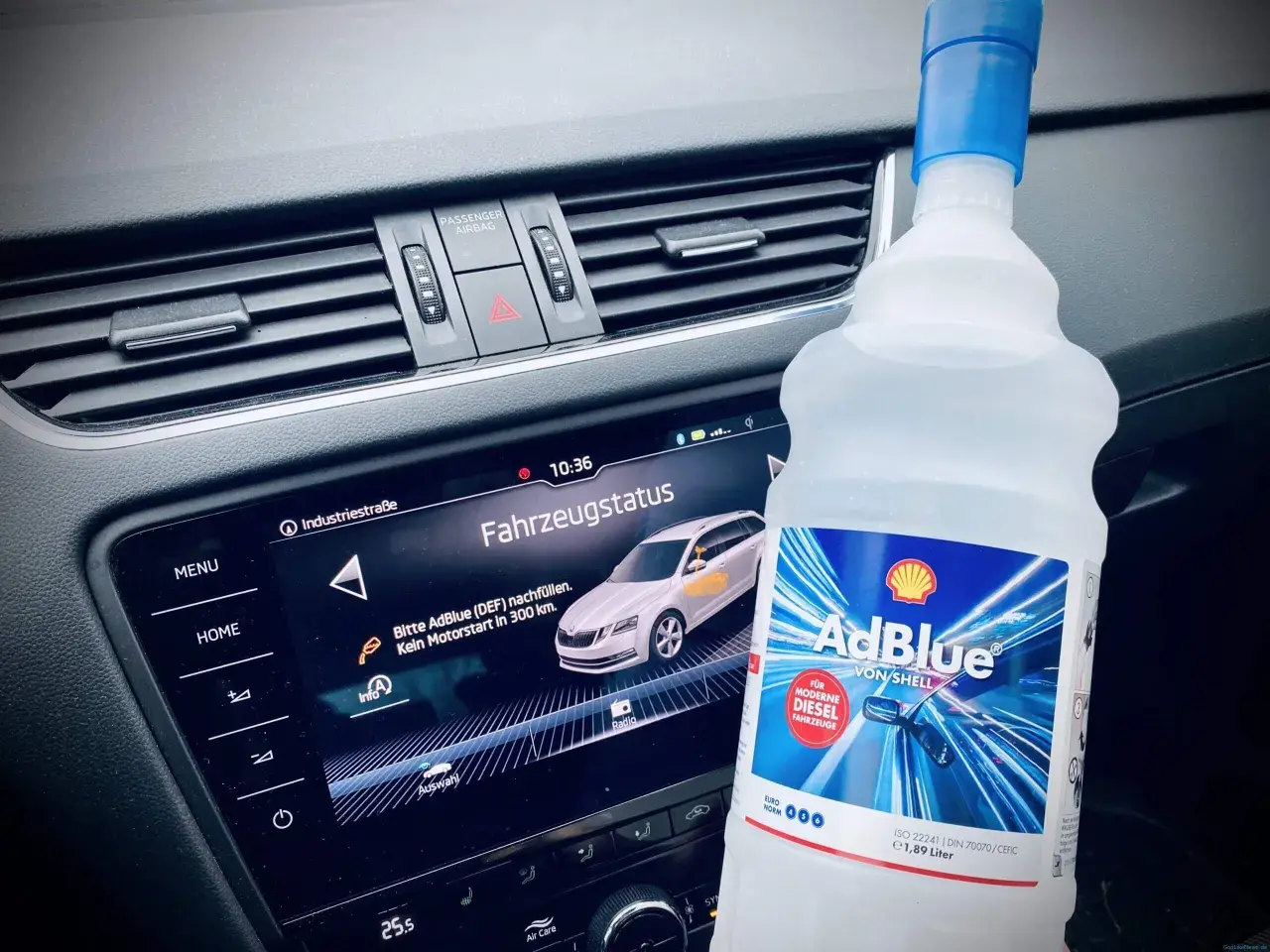 Flasche AdBlue neben dem Armaturenbrett. Fahrzeugstatus zeigt "Bitte AdBlue nachfüllen. Kein Motorstart in 300 km.