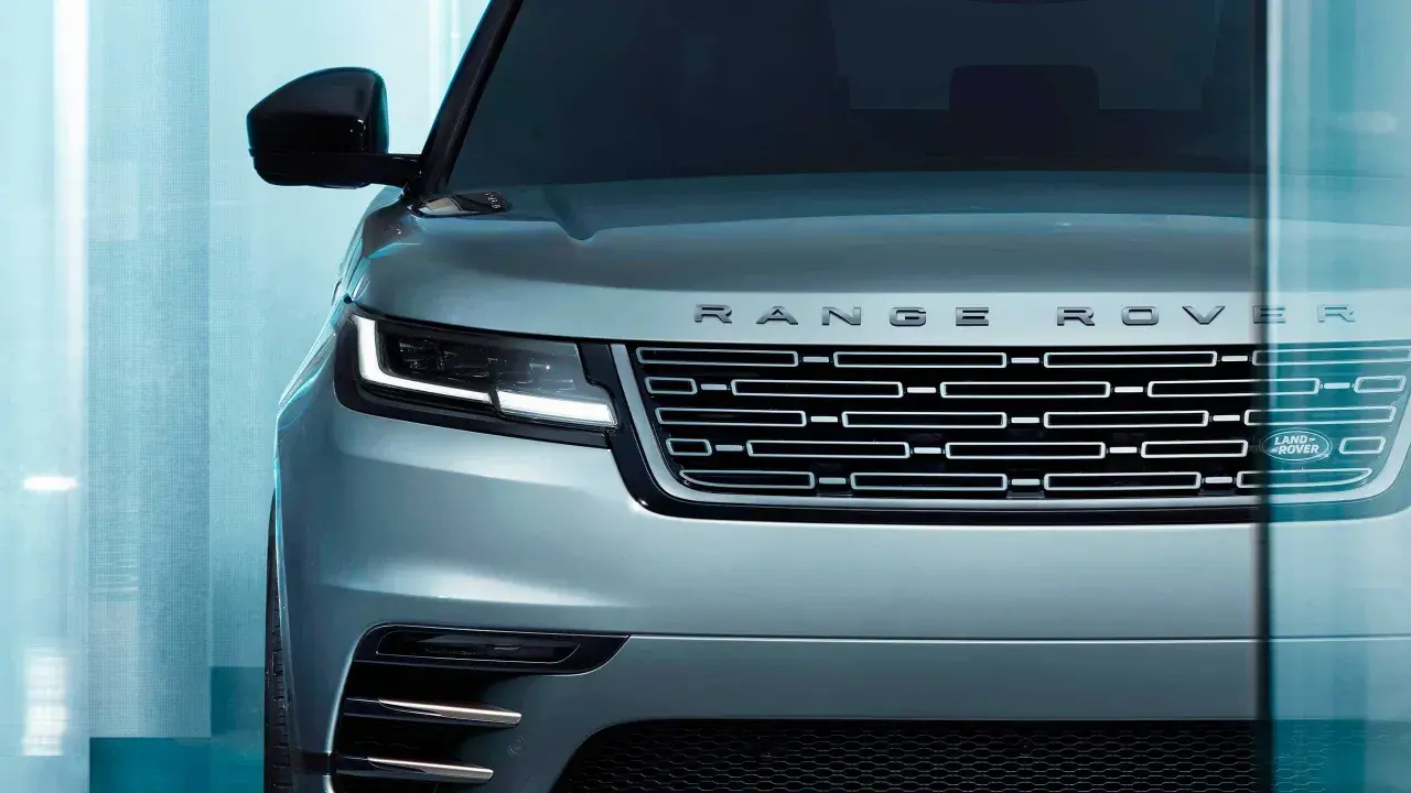 Der Kühlergrill eines silbernen Range Rover mit dem Schriftzug "RANGE ROVER" und dem Land Rover Logo. Ein Fahrzeug, das "land rover approved" ist.