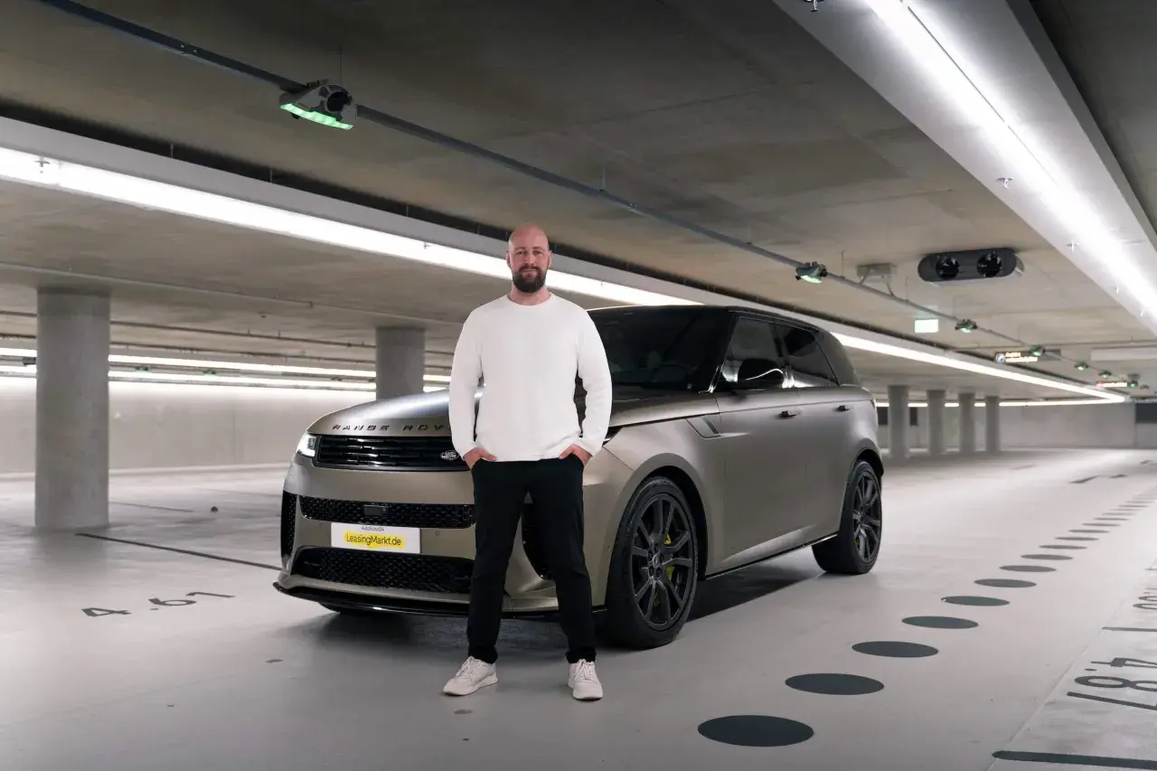 Mann steht neben einem Range Rover in einer Tiefgarage. Erste Range Rover Erfahrungen gesammelt.