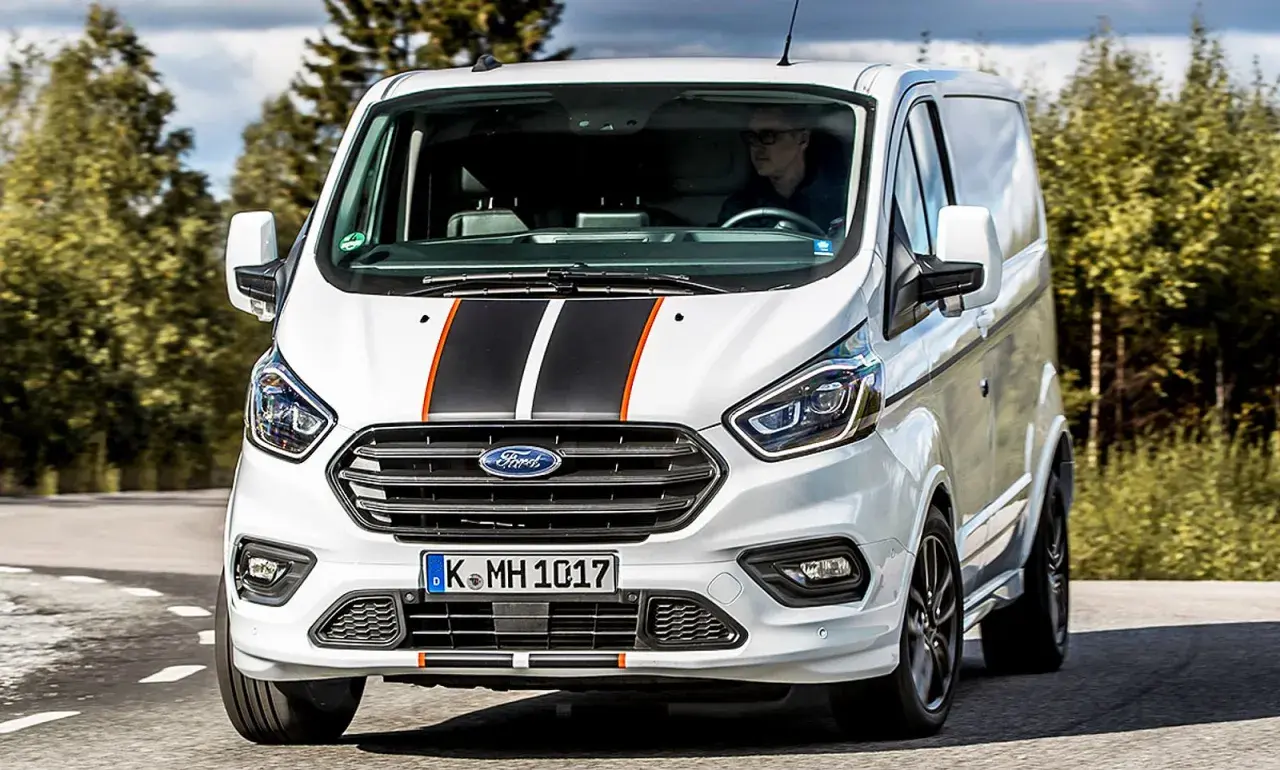 Weißer Ford Transit Custom mit Sportstreifen, Fahrer im Blick. Keine Probleme hier, nur ein stilvoller Transporter auf der Straße.