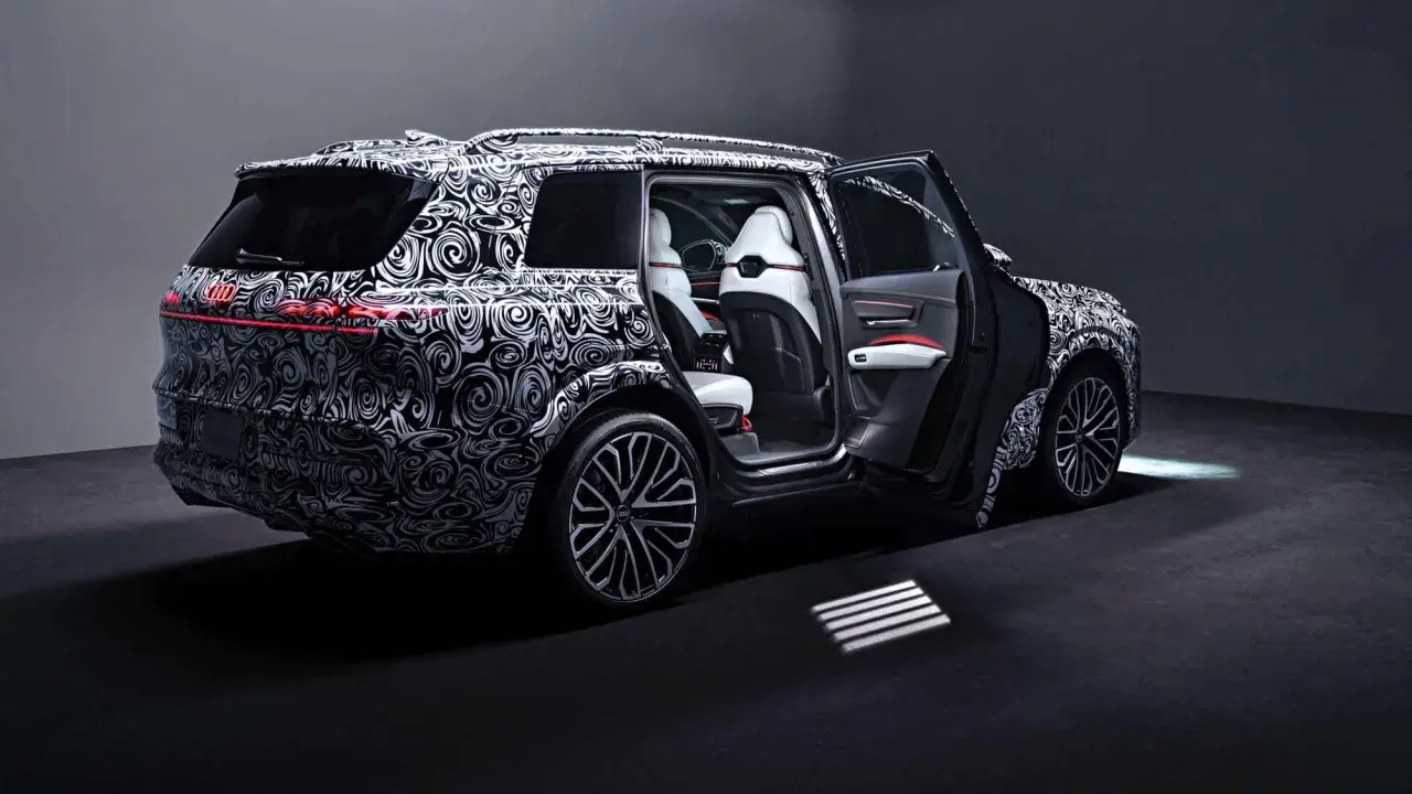 Der Audi SQ9, getarnt mit einem auffälligen Muster, zeigt seine luxuriösen weißen Ledersitze und die sportlichen Felgen.