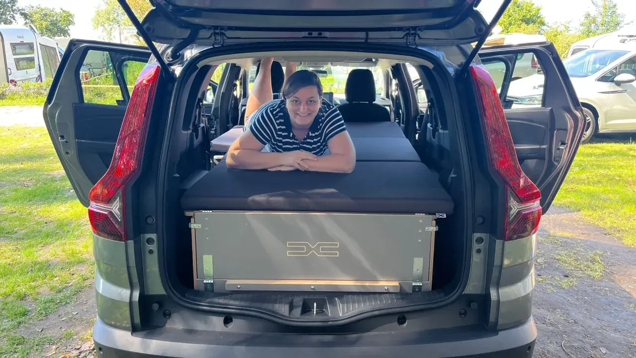 Frau liegt auf Bett im Dacia Jogger, bereit für den Camping-Test.