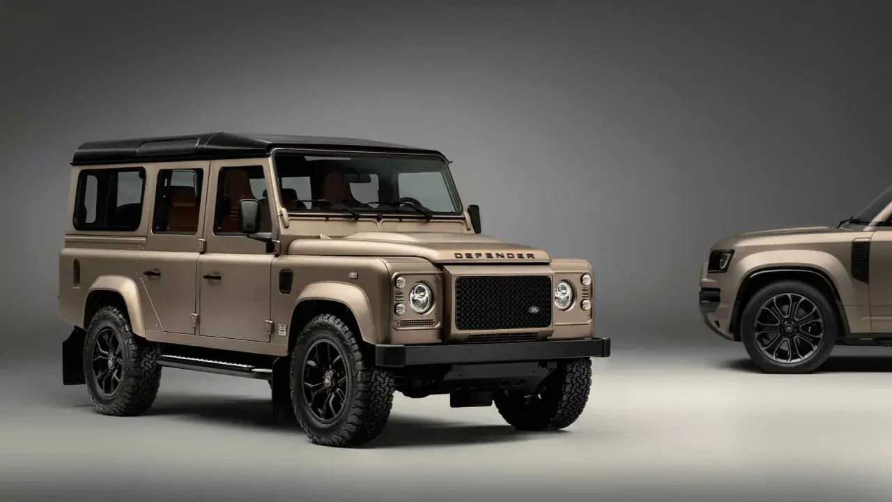 Zwei bronzefarbene Land Rover Defender stehen nebeneinander. Der vordere, klassische Defender ist bereit, wenn Sie einen Land Rover kaufen möchten.