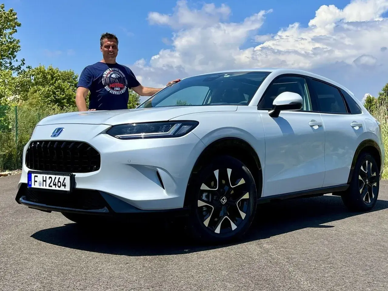 Mann steht neben einem weißen Honda ZR-V.