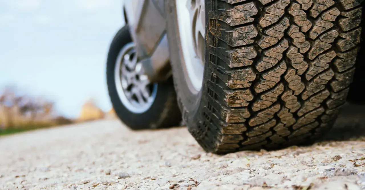 Detailaufnahme eines grobstolligen Offroadreifens, bereit für Abenteuer auf Schotterwegen.