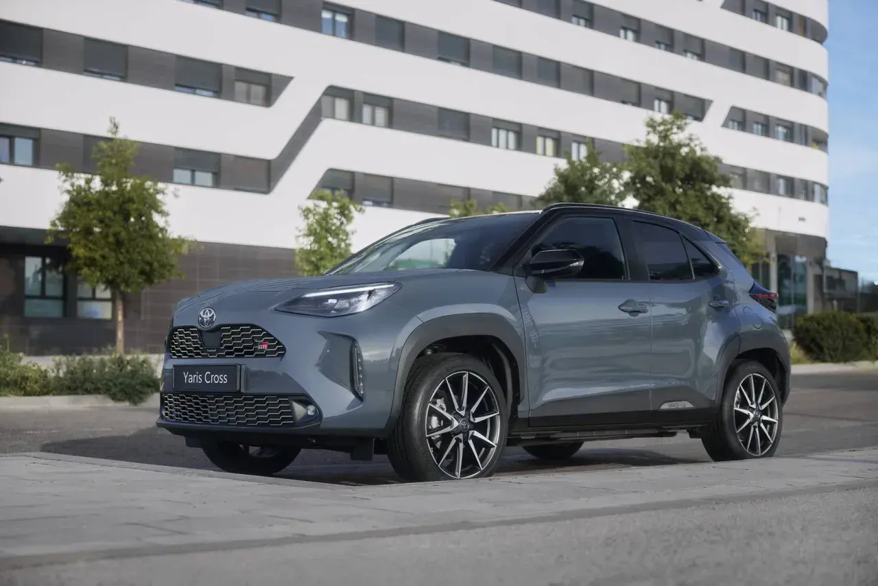 Grauer Toyota Yaris Cross 2026 mit GR-Sport-Akzenten steht vor einem modernen Gebäude.