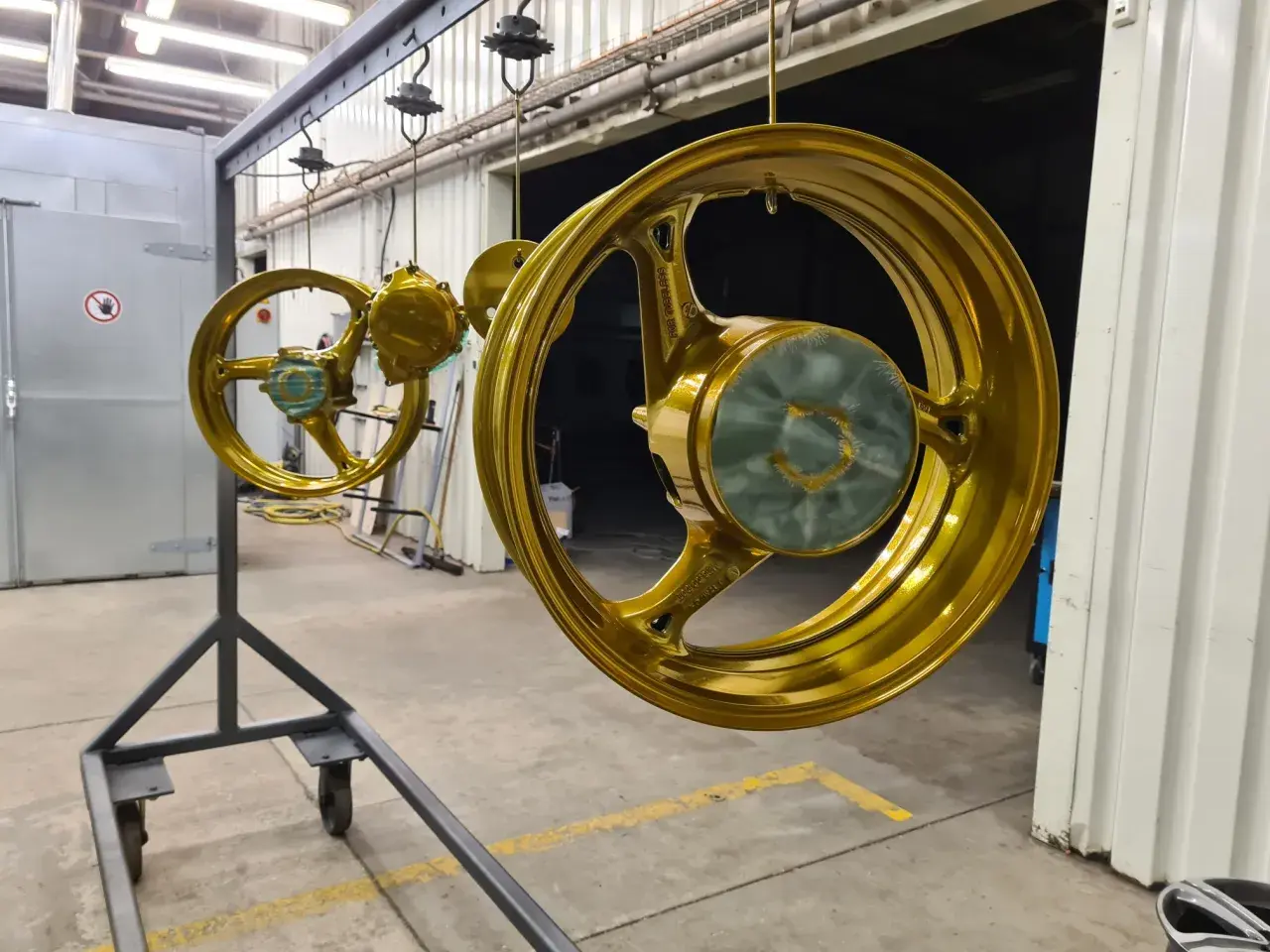 Goldene Felgen hängen zum Trocknen. Ein Prozess, der hilft, Felgen reparieren und ihnen neuen Glanz zu verleihen.