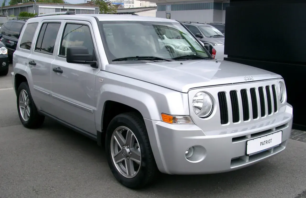 Silberner Jeep Patriot, der auf einem Parkplatz steht. Bekannt für seine Robustheit, aber auch für seine Jeep Patriot Schwachstellen, wie z.B. Rost an den Radläufen.