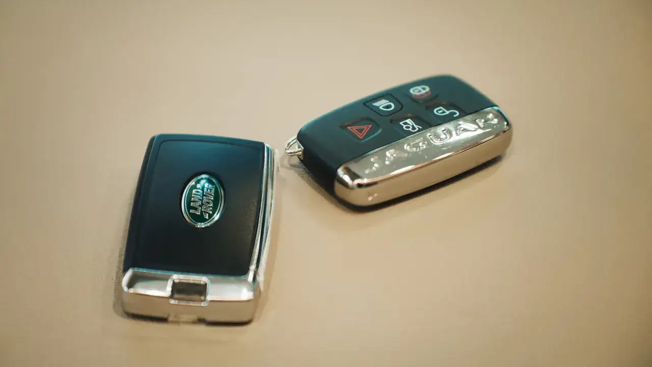 Zwei moderne Autoschlüssel liegen nebeneinander. Einer mit dem Land Rover Logo, der andere mit dem Jaguar Schriftzug.