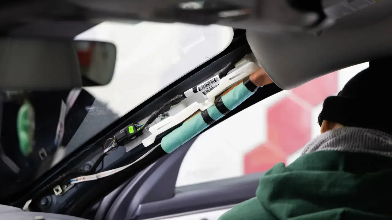 Ein Techniker rüstet eine Dashcam nach, indem er Kabel im Dachhimmel verlegt.