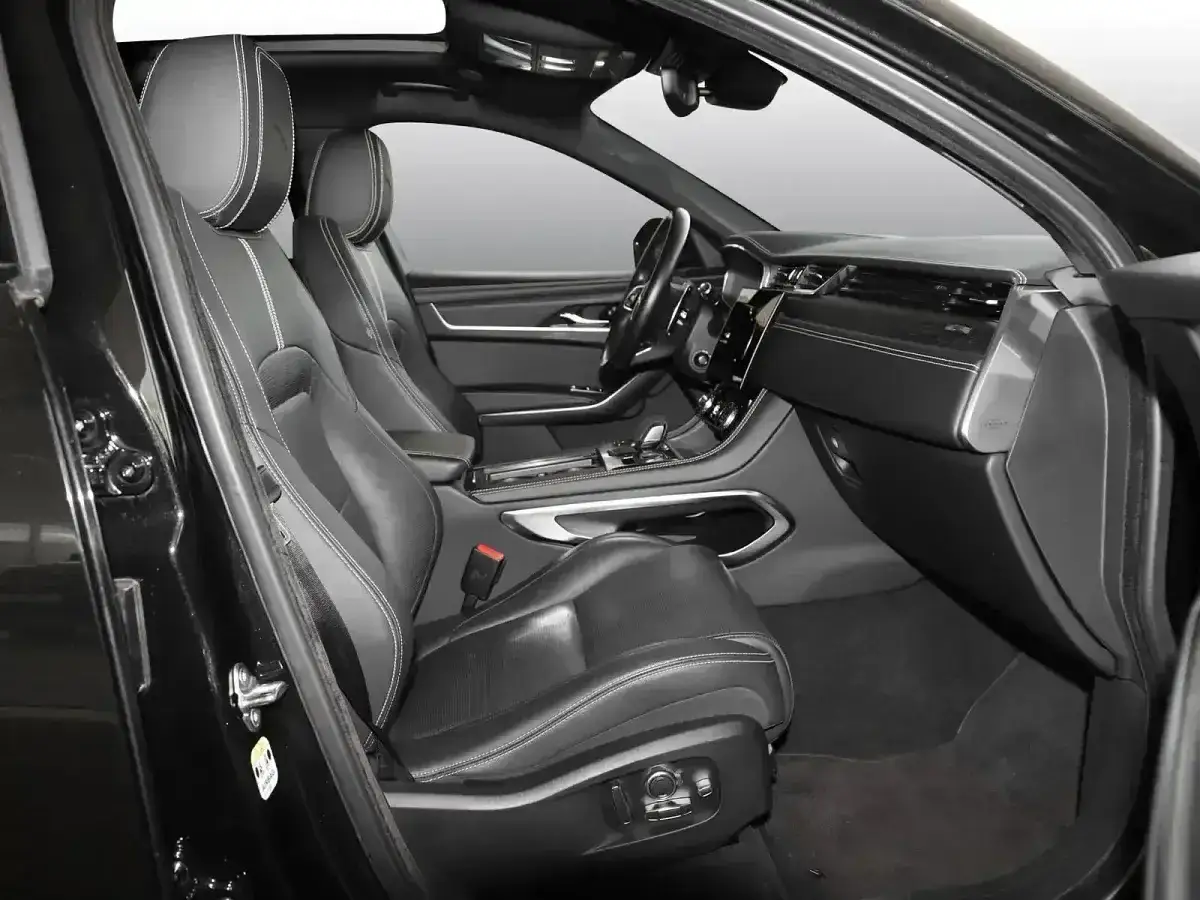 Innenraum eines schwarzen Jaguar F-Pace. Leder-Sportsitze mit weißen Nähten, Armaturenbrett und Mittelkonsole. Ein Blick auf den Jaguar F-Pace Test.
