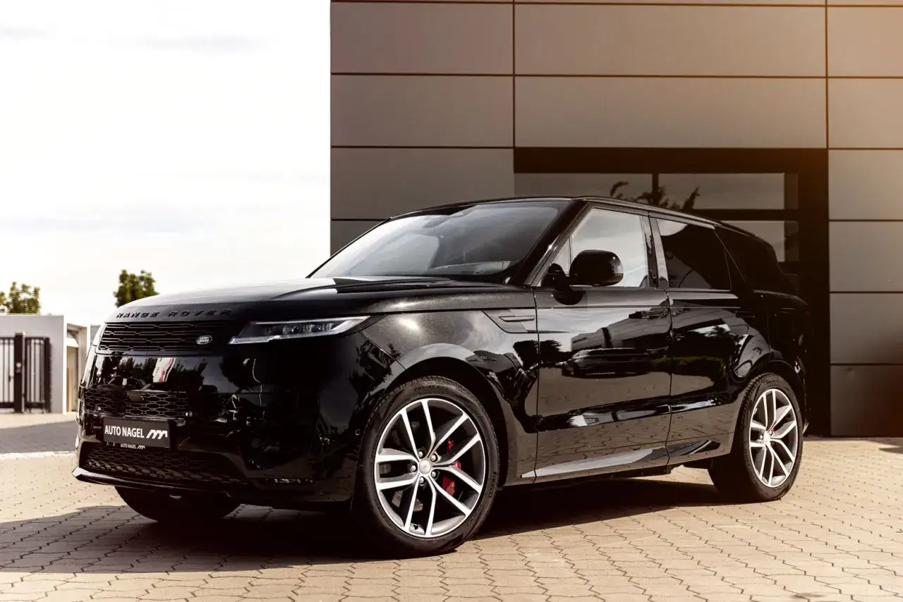 Glänzender schwarzer Range Rover Sport vor moderner Architektur. Positive Range Rover Erfahrungen sind garantiert mit diesem eleganten SUV.