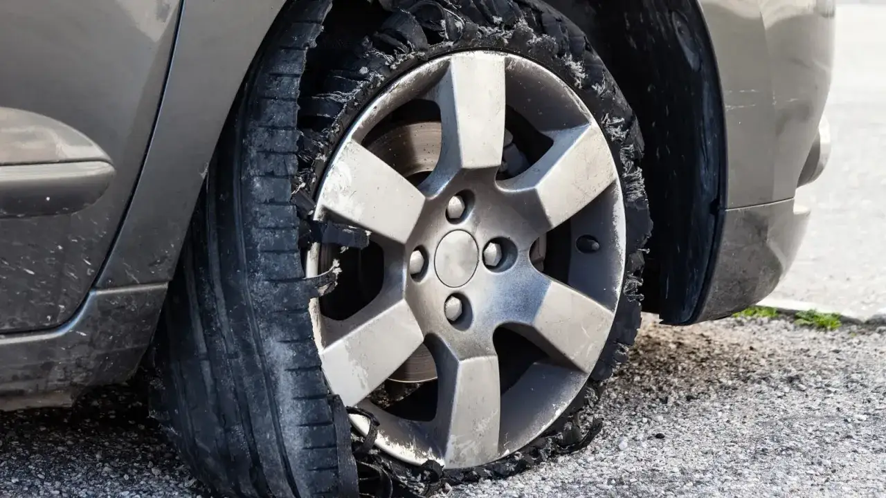 Ein Auto mit einem komplett zerstörten Reifen. Die Frage, wie lange ein Auto auf einem platten Reifen stehen kann, wird hier eindrucksvoll beantwortet: nicht lange.