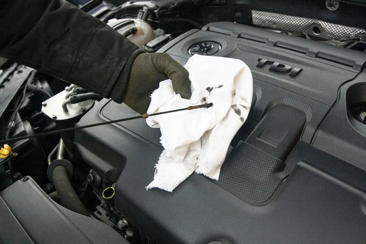 Hand mit Handschuh wischt &Ouml;lmessstab ab. Der &Ouml;lstand ist zu hoch bei diesem Dieselmotor.