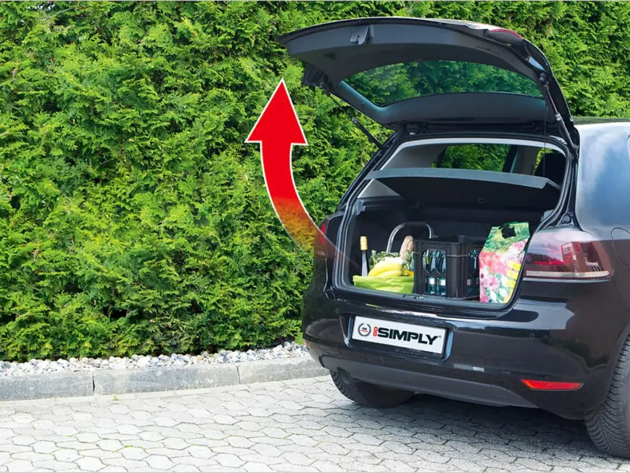 Ein roter Pfeil zeigt auf den geöffneten Kofferraum eines Autos, der mit Einkäufen beladen ist. Ideal, um den elektrischen Kofferraum nachrüsten.