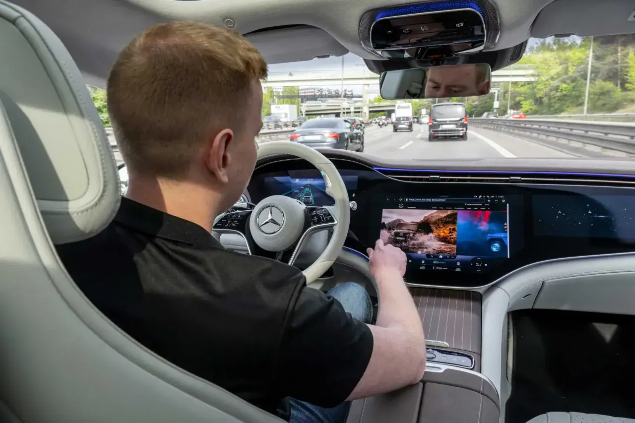 Mann im Mercedes mit aktiviertem Tempomat, der auf dem großen Display eine Route auswählt.