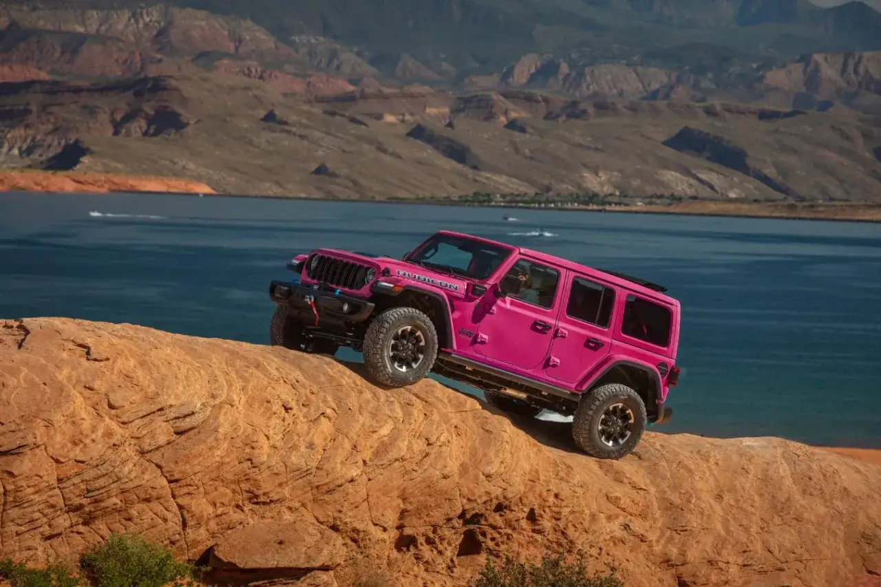 Pink Jeep Wrangler Rubicon klettert &uuml;ber Felsen. Trotz seiner Gel&auml;ndetauglichkeit gibt es bei Jeep Wrangler Schwachstellen, die man kennen sollte.