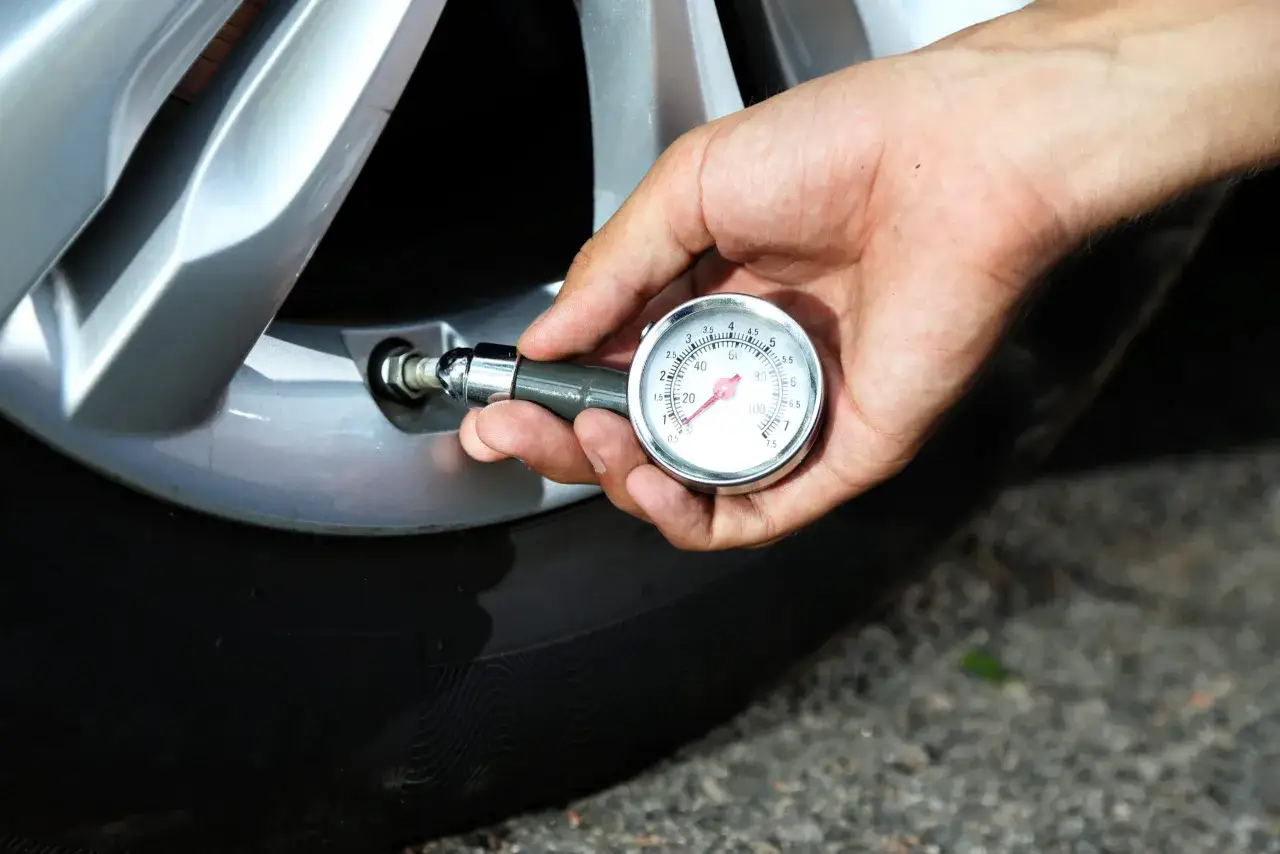 Hand prüft mit einem Manometer den Reifendruck. So lässt sich der Reifendruck korrigieren für mehr Sicherheit.