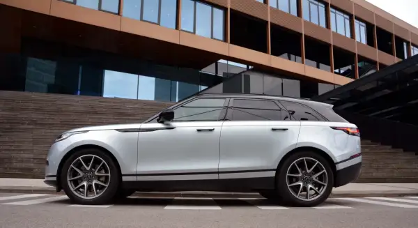 Silberner Range Rover Velar parkt vor moderner Architektur. Die eleganten Range Rover Velar Maße passen perfekt in das urbane Umfeld.